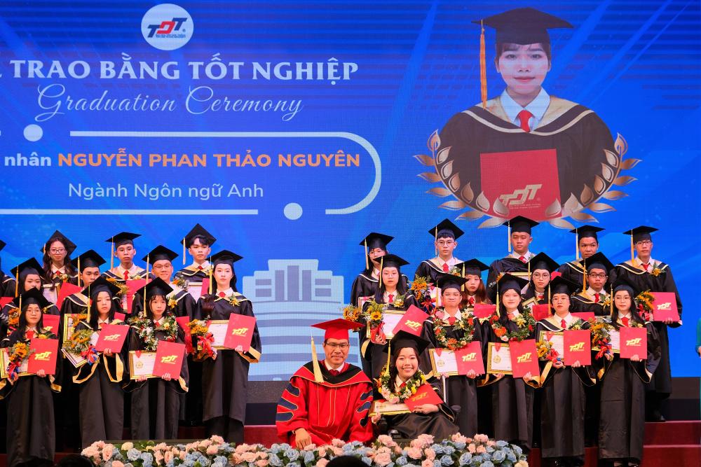 TS. Trần Trọng Đạo, Hiệu trưởng TDTU ngồi xuống trao bằng tốt nghiệp và chụp ảnh lưu niệm cùng tân cử nhân Nguyễn Phan Thảo Nguyên, sinh viên chuyên ngành Sư phạm, ngành Ngôn ngữ Anh, Khoa Ngoại ngữ - tốt nghiệp đạt loại Giỏi